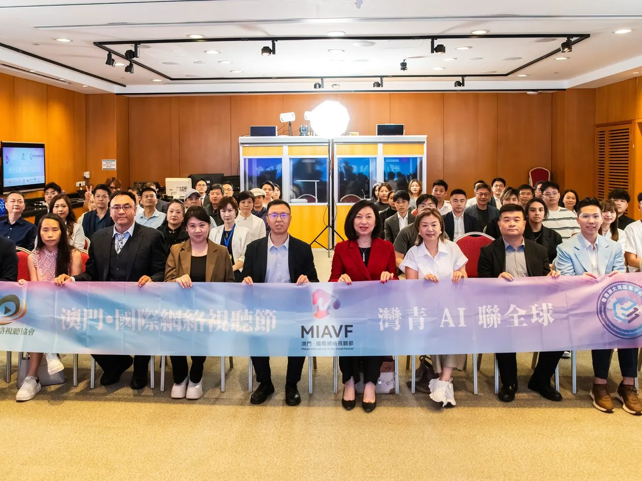 Group photo of 25+ Bay Youth AI delegates inside the Macao Science Centre auditorium holding the MIAVF / Bay Youth AI Connects The World banner, 2 June 2026