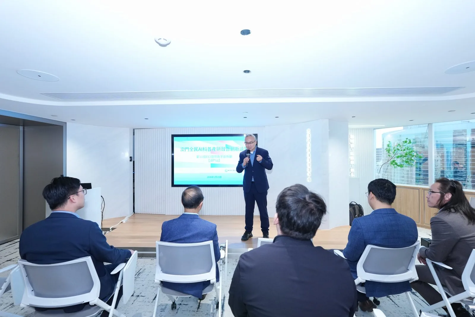 Wide hall — speaker on stage, audience in a circle