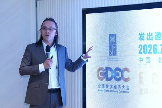 Long-haired keynote speaker in front of the Global Digital Economy Conference screen